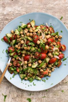 a blue bowl filled with salad and topped with lettuce, tomatoes, chickpeas