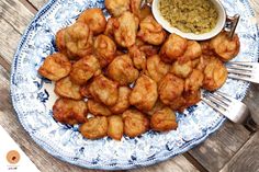 a blue and white plate topped with tater tots next to a bowl of dipping sauce