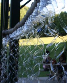 several plastic bottles hanging from a chain link fence