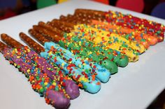 a white plate topped with lots of colorful donuts covered in sprinkles