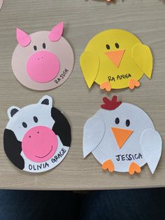 four farm animals cut out from paper on a table with name tags attached to them