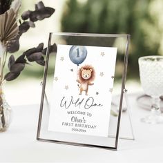 a welcome sign for a first birthday with a lion on it and balloons in the air