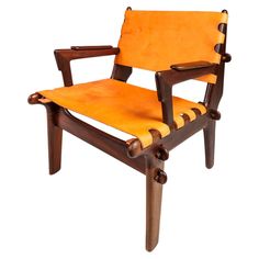 a wooden chair with an orange leather seat and arm rests against a white background,