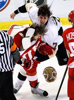 two hockey players colliding with each other in front of an official on the ice