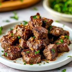 a white plate topped with meat covered in sauce and garnished with parsley