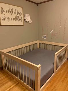 a baby's room with a crib and wooden floors, painted in light gray