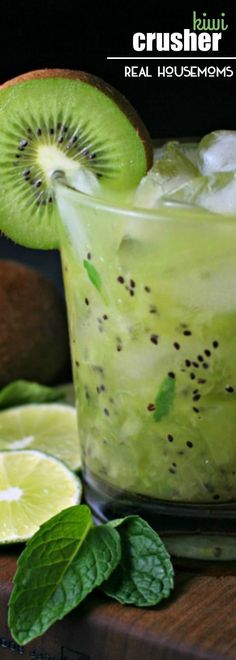 a kiwi drink in a glass with ice and mint on the rim next to sliced kiwis