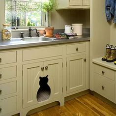 a kitchen with wooden floors and white cupboards has a cat hole in the wall