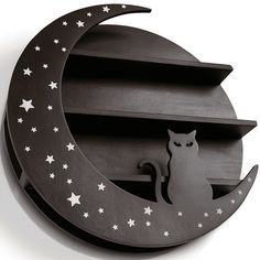 a metal cat sitting on the moon with stars in it's shadow, next to a shelf