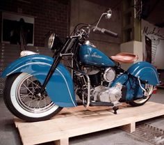 a blue motorcycle sitting on top of a wooden platform