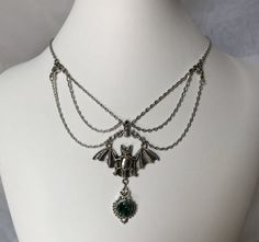 This gothic vampire inspired necklace is made with an antiqued silver plated bat. filigrees and findings, accented with sparkling glass crystals in EMERALD GREEN. Decorated portion is 6" wide and centerpiece is 2 7/8" tall in the center.Necklace is adjustable 15-18" with a lobster clasp and chain extender in the back. If you would like a different length or stone color, please send us a message. Wedding Goth, Goth Accessories, Vampire Queen, Onyx Crystal, Gothic Vampire, Garnet Crystal, Filigree Necklaces, Gothic Victorian, Dark Sapphire