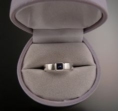 "This is a sturdy ring that contains a 4mm square natural deep blue/purple Iolite. The stone is bezel set on a 2mm thick by 4mm wide sterling silver band. It is sturdy and comfortable to wear. I can make this ring for you in any size between 4 and 9. Iolite is a very true blue natural stone found in Bolivia. It rates a 7 on the Mohs scale for hardness. The stones are very clean top blue color and well cut. Be aware that in ring sizes smaller than 7 the stone will look slightly larger in scale wi Purple Birthstone Ring In Sterling Silver With Bezel Setting, Sterling Silver Sapphire Ring With Rectangular Stone, Sterling Silver Sapphire Three-stone Jewelry, Silver Faceted Sapphire Ring For Gift, Elegant Square-cut Sapphire Ring In Sterling Silver, Mohs Scale, Square Stone, Ring Sizes, True Blue