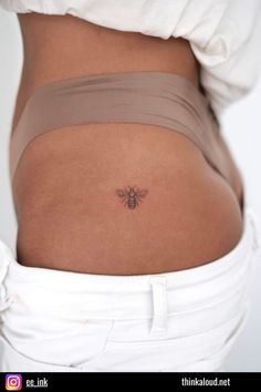 a woman's stomach with a small bee tattoo on the side of her belly