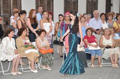 a woman in a blue dress is walking down the runway with other people behind her