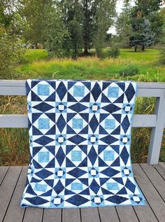 a blue and white quilt sitting on top of a wooden deck