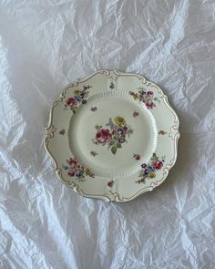 a white plate with flowers on it sitting on a piece of paper covered in plastic