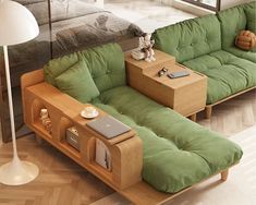 a green couch sitting next to a wooden coffee table on top of a hard wood floor