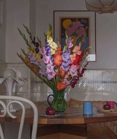 a vase filled with colorful flowers sitting on top of a table next to two chairs