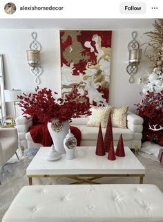 a living room decorated for christmas with white furniture and red decorations on the wall behind it