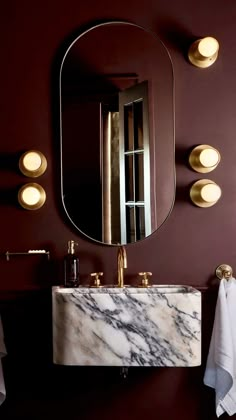 a bathroom sink sitting under a large mirror next to a wall mounted faucet