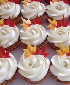 cupcakes with white frosting and autumn leaves on them are arranged in rows