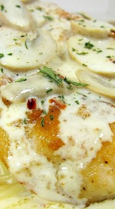 a close up of food on a plate with onions and cheese sauce in the background