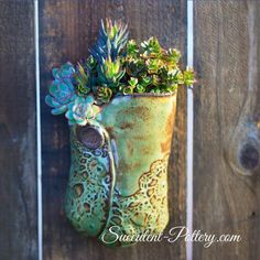 a planter with succulents in it hanging on a wooden fence post