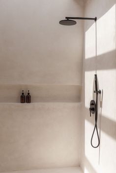 the shower head and hand shower are next to each other in this white walled bathroom