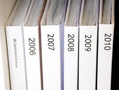 a row of white books sitting on top of a book shelf next to each other