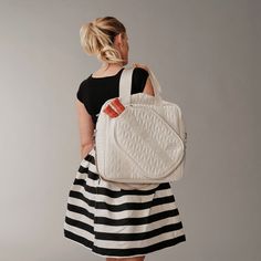 a woman in a black and white striped dress carrying a handbag on her back