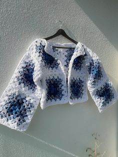 a crocheted jacket hanging on a wall