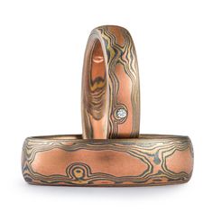 "This gorgeous matching Mokume Gane ring set features our Woodgrain pattern, Fire palette, both with etched finishes, and low dome profiles. The Fire palette metal combination is comprised of 14k Red gold, 14k Yellow Gold, and Sterling Silver. The thinner ring also has 3 lovely flush set stones. Ring 1 Width Shown: 4mm Size Shown: 6.25 Pattern: Woodgrain Palette: Fire Finish: Etched & Oxidized Profile: Low Dome Stones: 1.75mm sapphire, two 1.20mm diamonds Setting: Flush Ring 2 Width Shown: 6 Round Patina Rings For Anniversary, Carved Rings For Anniversary, Flush Ring, Mokume Gane Ring, Woodgrain Pattern, Custom Wedding Rings, Mokume Gane, Pattern Ring, Diamond Settings