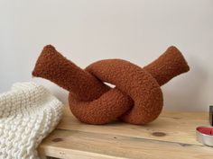 a knitted knot sitting on top of a wooden table next to a coffee maker