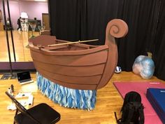 a wooden boat sitting on top of a hard wood floor next to yoga mats and an exercise mat