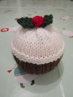 a knitted cupcake with a red rose on top sitting on a white table