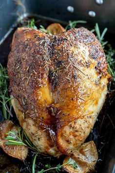 a close up of a chicken in a pan with potatoes and herbs on the side