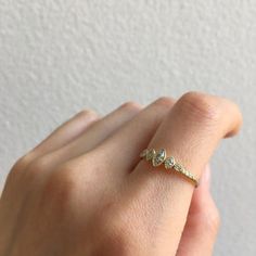 a woman's hand wearing a gold ring with three small diamonds on the band