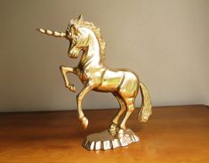 a golden unicorn figurine sitting on top of a wooden table