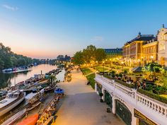 boats are parked along the side of a river at dusk in front of a large building