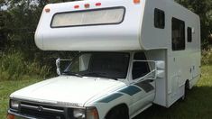 an rv is parked in the grass with its hood up on it's side