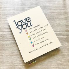 a card with the words love you on it sitting on top of a wooden table