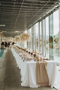 a long table with white linens and flowers on it