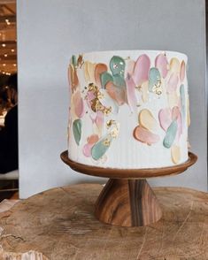 a white and pink cake sitting on top of a wooden table next to a wall