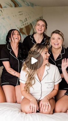 a group of women in black and white pajamas sitting on top of a bed together