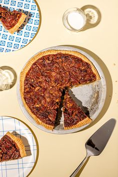 a pecan pie with one slice missing from it and two plates on the table