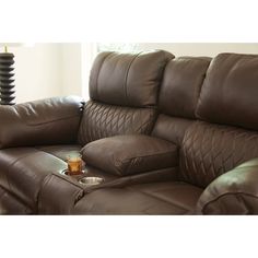 a brown leather reclining couch with a drink on the armrest and foot rest