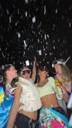 three women in swimsuits and sun glasses are having fun with confetti