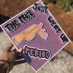 a person holding up a purple graduation cap