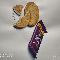 a piece of cracker next to a chocolate bar on a white tablecloth with the word dairy milk printed on it