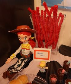 a table topped with lots of different types of candies and desserts next to a glass vase filled with strawberries